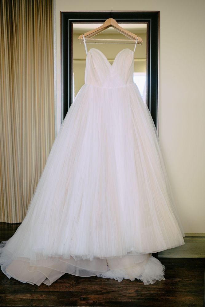 A full tulle wedding gown on a hanger in front of the studio mirror