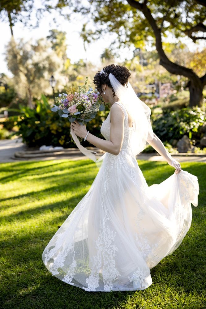 A lace gown with the train fanned out across a lawn