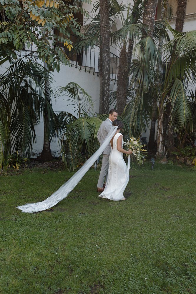 A gown with a long train trailing across grass in a garden