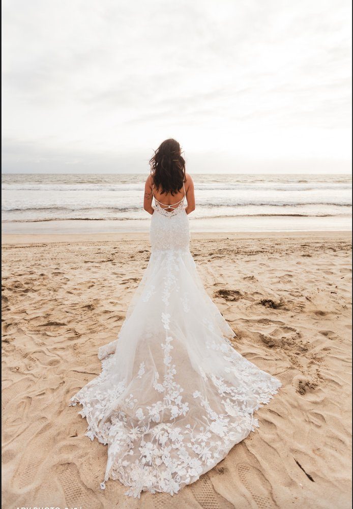 A fitted lace gown photographed from behind on a beach